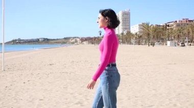 Giyinik genç kadın denize gider ve ileriye bakar.