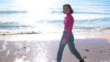 Kıyı şeridi boyunca giyinmiş ve gülümseyen genç bir kadın.