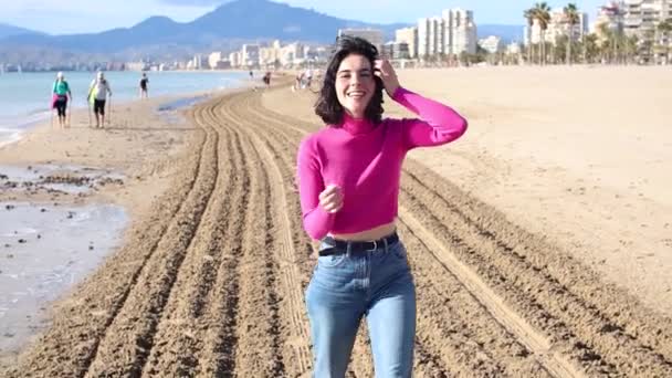 Mujer joven vestida va a lo largo de la costa y sonriendo, cámara lenta — Vídeo de stock