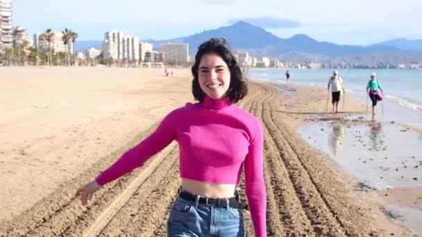 Happy young woman goes along the coastline and smiling — Stockvideo