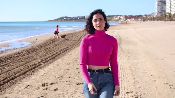 Dressed young woman goes along the coastline and smiling, slow motion — Video