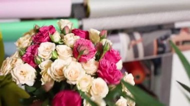 Çiçekçide bir kadın satmak için bir gül hazırlıyor.