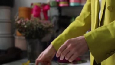 Florist in a flower salon prepares a bouquet of white flowers for sale