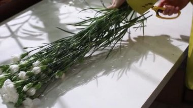 Çiçekçide bir kadın satılık beyaz çiçekli bir buket hazırlar.