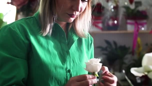 Mulher em um salão de flores prepara uma rosa para vender — Vídeo de Stock