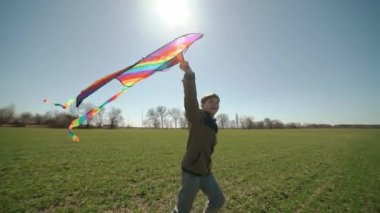 Mutlu bir çocuk uçan bir gökkuşağı uçurtmasıyla oynuyor.. 