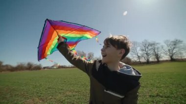 Mutlu bir çocuk uçan bir gökkuşağı uçurtmasıyla oynuyor.. 