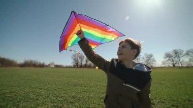 Mutlu bir çocuk uçan bir gökkuşağı uçurtmasıyla oynuyor.. 