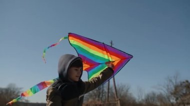 Gökkuşağı uçurtması olan mutlu bir çocuk bisiklet sürüyor..