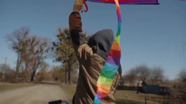 Gökkuşağı uçurtması olan mutlu bir çocuk bisiklet sürüyor..