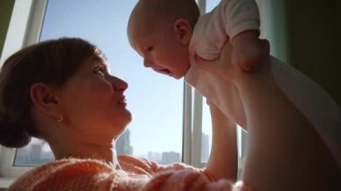 Happy young mother throws her baby up and kisses.