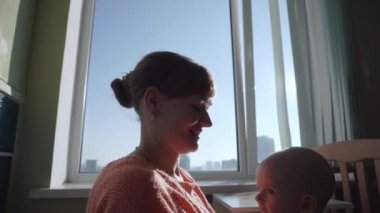Happy young mother throws her baby up and kisses.