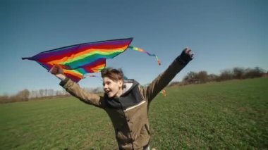 Mutlu bir çocuk uçan bir gökkuşağı uçurtmasıyla oynuyor.. 