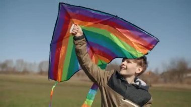 Mutlu bir çocuk uçan bir gökkuşağı uçurtmasıyla oynuyor.. 