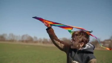 Mutlu bir çocuk uçan bir gökkuşağı uçurtmasıyla oynuyor.. 