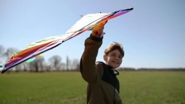 Mutlu bir çocuk uçan bir gökkuşağı uçurtmasıyla oynuyor.. 