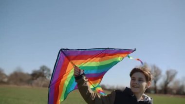 Mutlu bir çocuk uçan bir gökkuşağı uçurtmasıyla oynuyor.. 