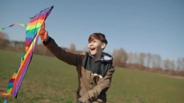 Mutlu bir çocuk uçan bir gökkuşağı uçurtmasıyla oynuyor.. 