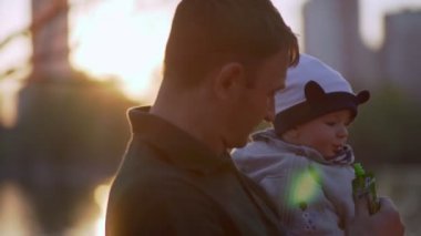 Genç anne ve baba kollarındaki gölette bebeği besliyorlar..