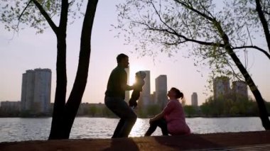 Babam bebeği kollarında ve dairelerinde tutuyor, annem de hayran. Aile silueti.