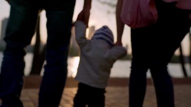 Young mother and father teach the child to walk along the path.