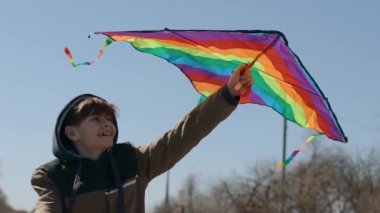 Mutlu bir çocuk uçan bir gökkuşağı uçurtmasıyla oynuyor.. 