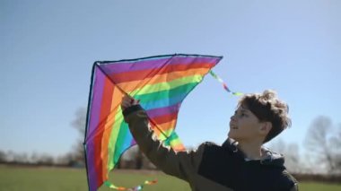 Mutlu bir çocuk uçan bir gökkuşağı uçurtmasıyla oynuyor.. 