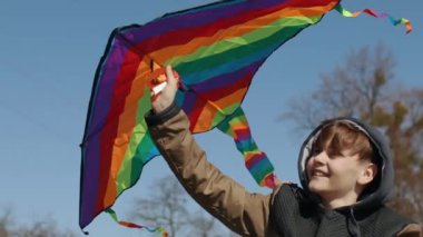 Mutlu bir çocuk uçan bir gökkuşağı uçurtmasıyla oynuyor.. 