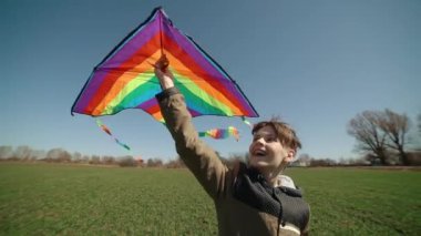 Mutlu bir çocuk uçan bir gökkuşağı uçurtmasıyla oynuyor.. 