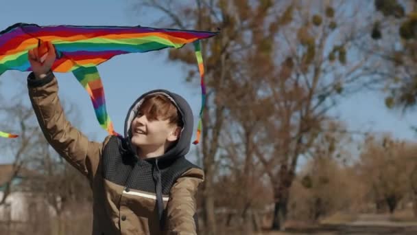 A happy boy with a flying rainbow kite rides a bicycle on the road. — 비디오