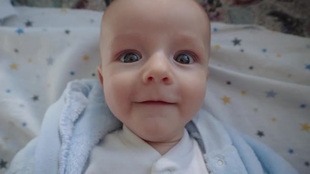 Funny child lies in bed, looks at the camera and shows different emotions. — Stok video