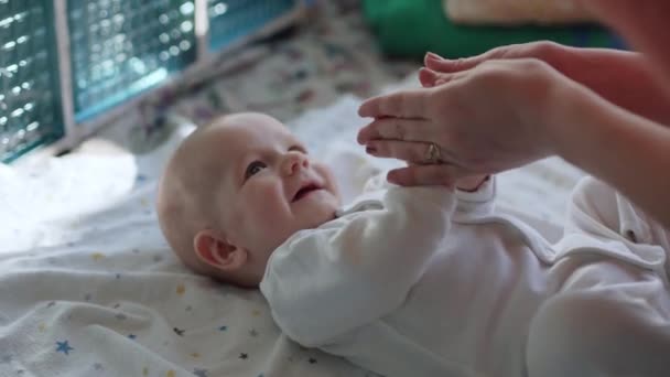 Una madre cariñosa juega con sus bebés desnudos brazos. — Vídeos de Stock
