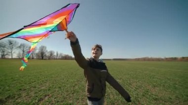 Mutlu bir çocuk uçan bir gökkuşağı uçurtmasıyla oynuyor.. 