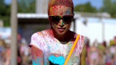 Holi 'nin resimlerini elinde tutan mutlu kız onları kameraya üflüyor..