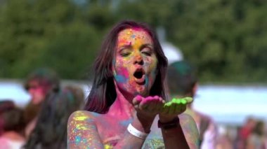Holi 'nin resimlerini elinde tutan mutlu kız onları kameraya üflüyor..