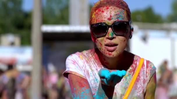 Happy girl holding Holi paints in her hands, blowing them into the camera. — Stock video