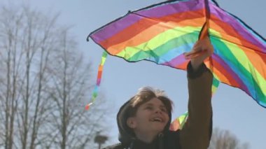 Mutlu bir çocuk uçan bir gökkuşağı uçurtmasıyla oynuyor.. 