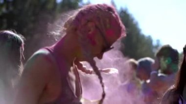 Holi Festivali 'nde gülümseyen ve başını renkli boyalarla sallayan çekici genç bir kadının portresi.