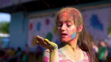 Holi 'yi elinde tutan mutlu kız resimlerini üflüyor. Holi festivalinde.