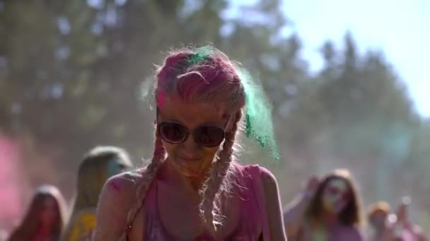 Portrét atraktivní mladé ženy usmívající se a potřásající hlavou pokrytou barevnou barvou na festivalu Holi