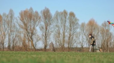 Bir çocuk elinde uçurtmayla yeşil bir arazide koşuyor. Yan görüntü, yavaş çekim. Yüksek kaliteli FullHD görüntüler