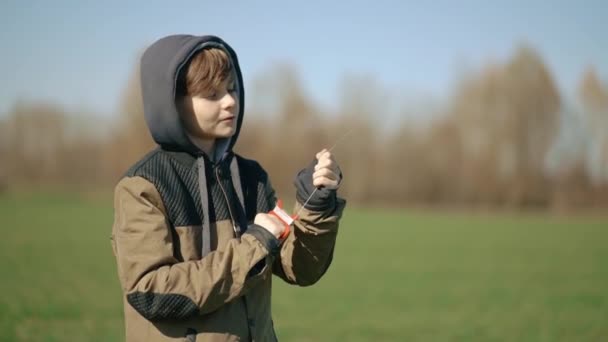 Chłopiec Trzyma Rękach Żyłkę Wędkarską Odpala Wielobarwny Latawiec Dostosowując Wysokość — Wideo stockowe