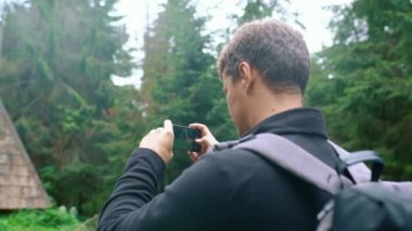 Genç bir adam, bir turist, cep telefonuyla güzel bir fotoğraf çekiyor. Yakın plan. Yan görüş. Seyahat fotoğrafı konsepti