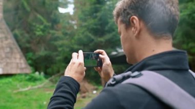 Genç bir adam, bir turist, bir arkadaşının güzel bir fotoğrafını cep telefonuyla çekiyor. Yakın plan. Seyahat fotoğrafı konsepti.