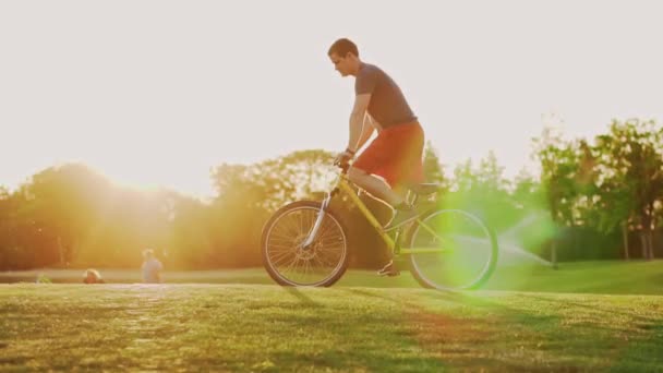Napnyugtakor Biciklizik Gyepen Egy Biciklis Sziluettje Aki Lassan Lovagol Kiváló — Stock videók