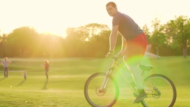 Jízda na kole po trávníku při západu slunce. Silueta cyklisty jedoucího pomalu. Vysoká kvalita 4k záběry zpomalení.