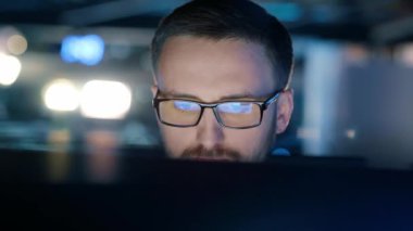 Bilgisayarda çalışan, bilgisayarın yansıması olan bir bilgisayar ekranına bakan, interneti kullanan, okuyan, izleyen, geç saatlere kadar çalışan odaklanmış bir adamın yakın çekimi. Yüksek kalite 4k görüntü