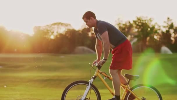 Napnyugtakor Biciklizik Gyepen Egy Biciklis Sziluettje Aki Lassan Lovagol Kiváló — Stock videók