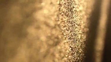 Yavaş çekimde siyah bir arkaplanda yüzen toz parçacıklarının güzel parıltısı. Bokeh etkisi. Çözülmüş altın parçacıkların arka planı. Soyutlama. Havada yüzen gerçek toz parçacıkları.