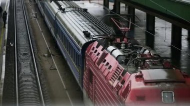 Tren raylar boyunca hareket eder ve istasyona varır. İstasyondan kalkan bir yolcu treni. Yukarıdan görüntüle